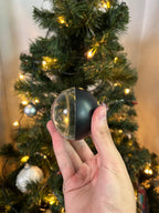 Memory Orb in black, held in front of a Christmas tree